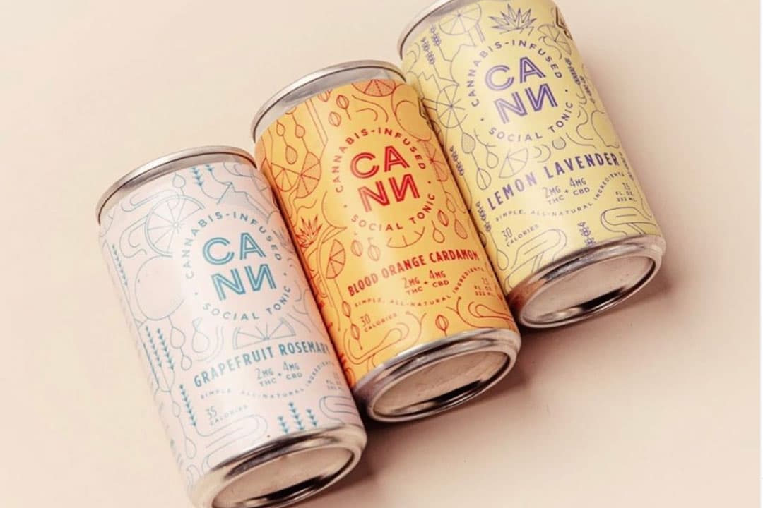 Three Cann cannabis-infused social tonic cans in grapefruit rosemary, blood orange cardamom, and lemon lavender