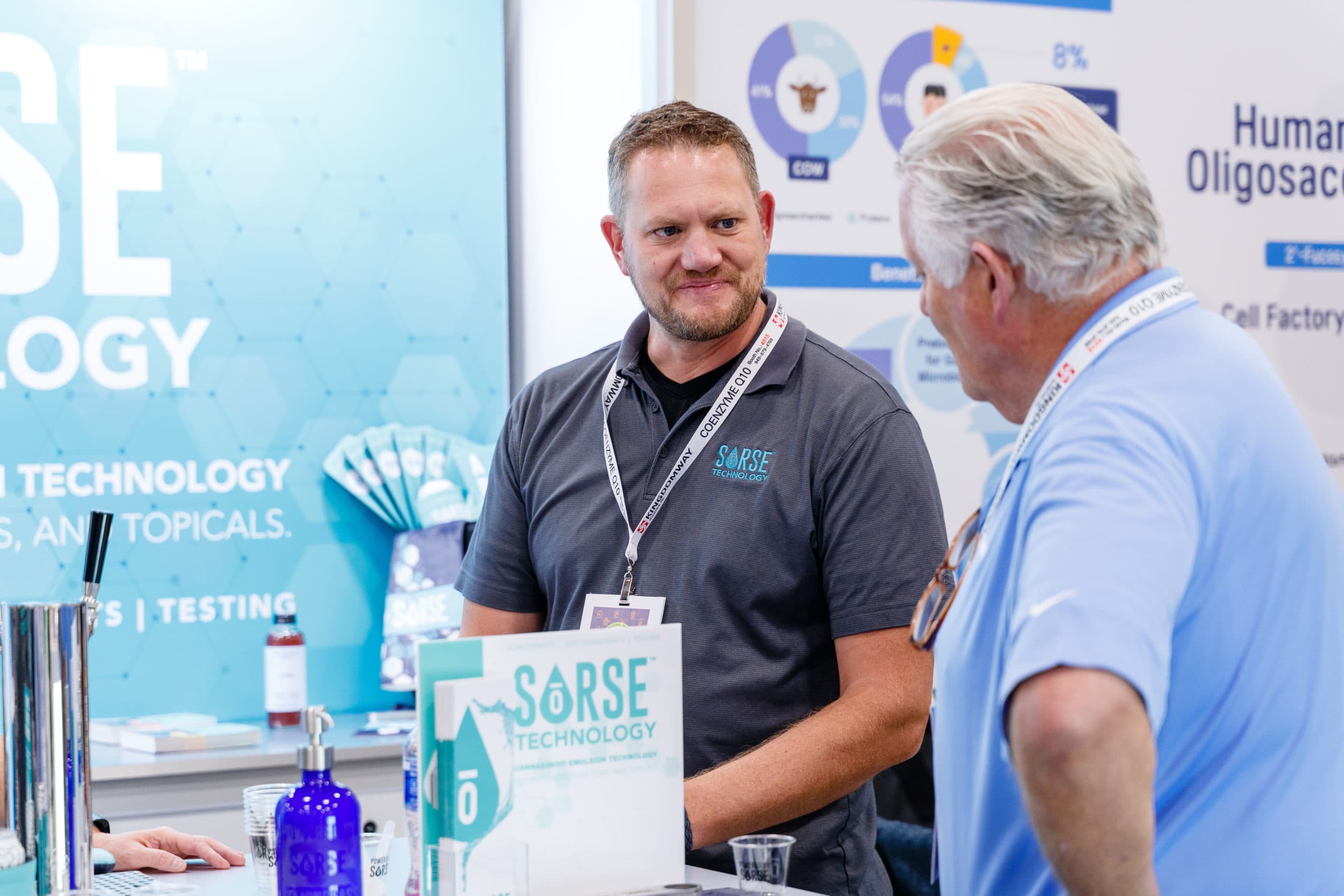 A SōRSE team member talking with a visitor at the SōRSE trade show booth