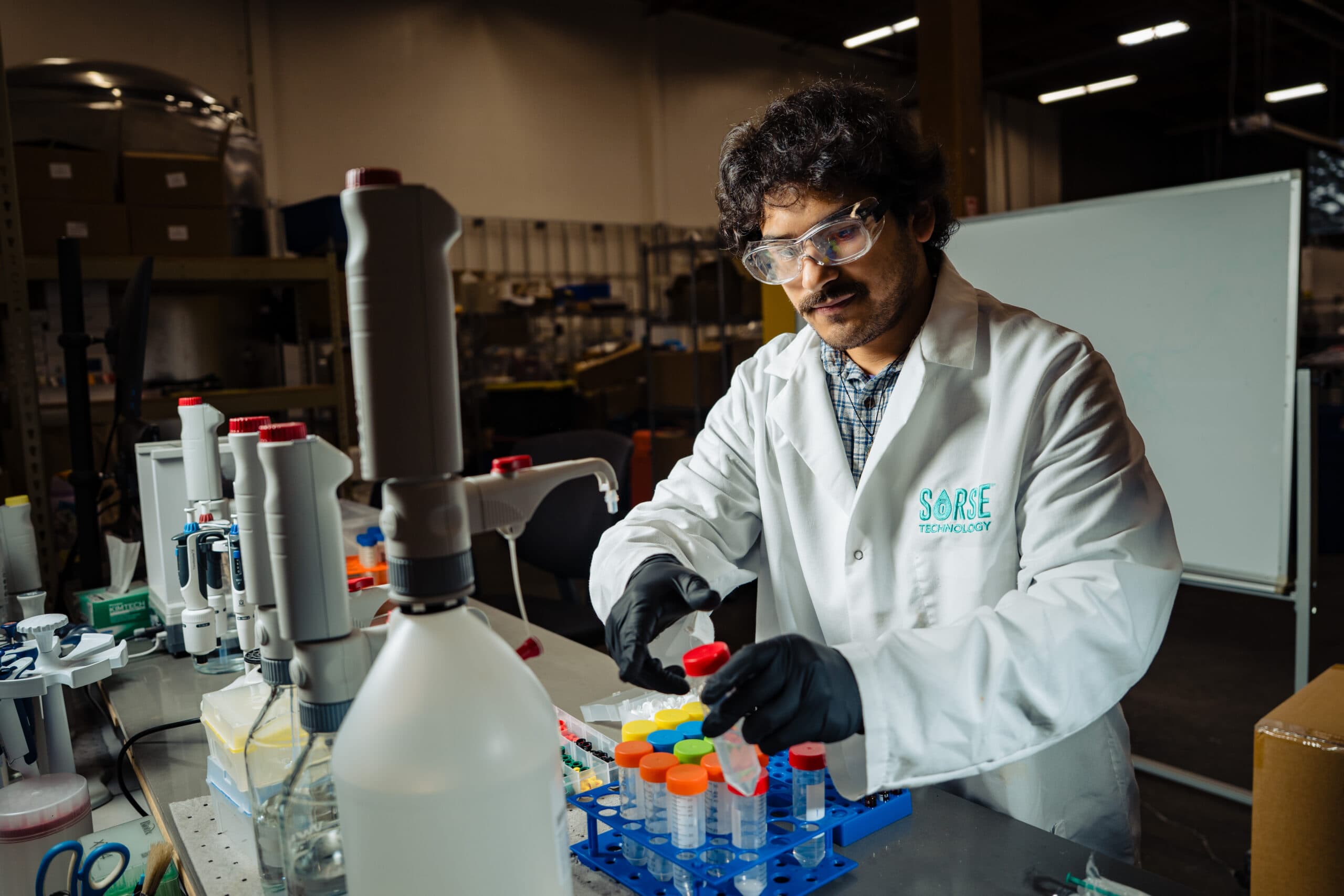 SōRSE scientist dispensing liquid into sample tubes at a lab bench