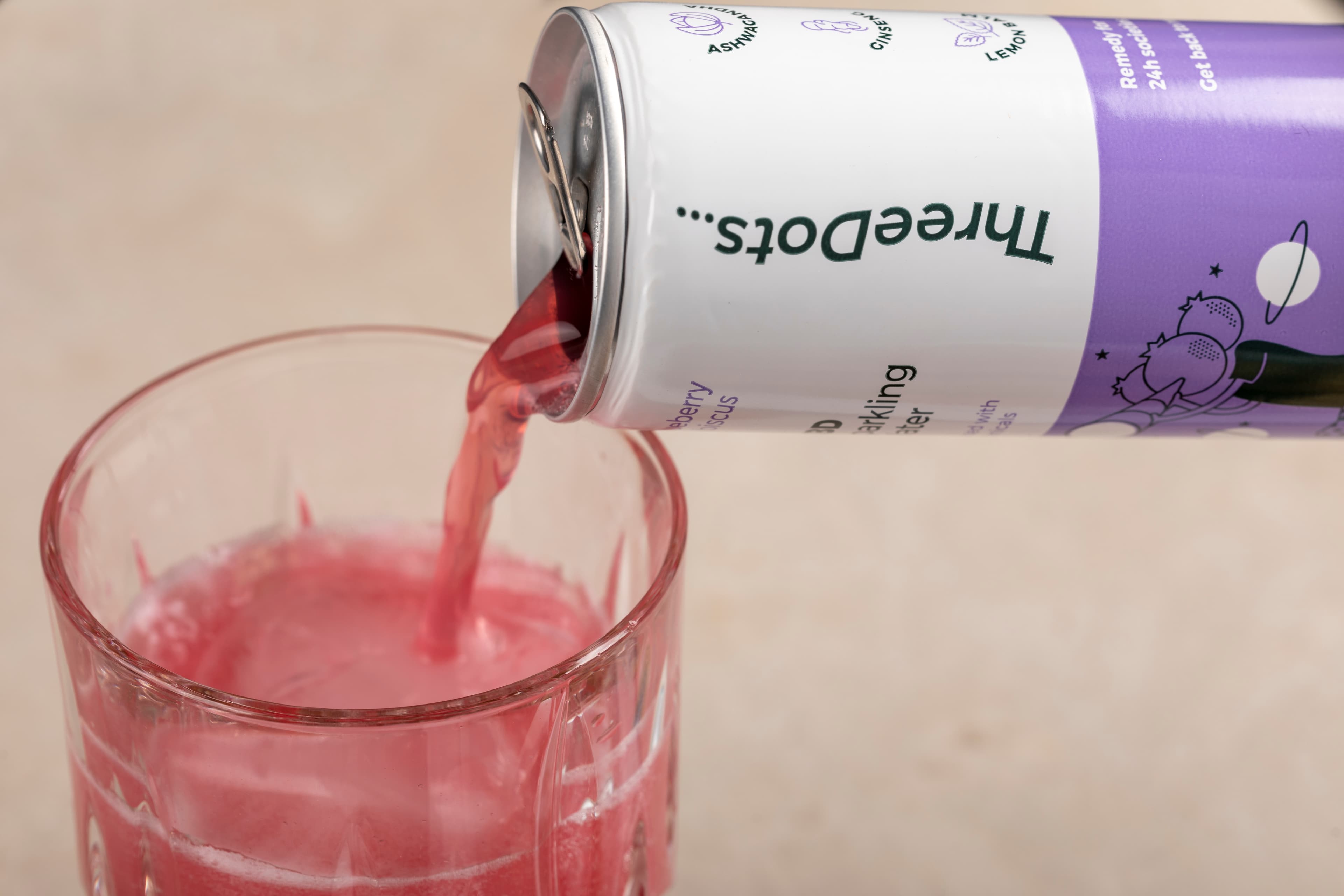 A pink ThreeDots sparkling drink pouring from a can into a glass