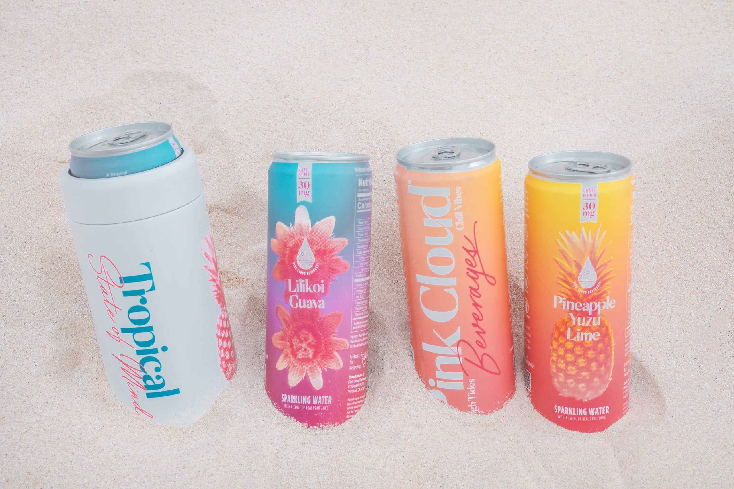 Four Pink Cloud hemp-infused sparkling water cans standing in beach sand